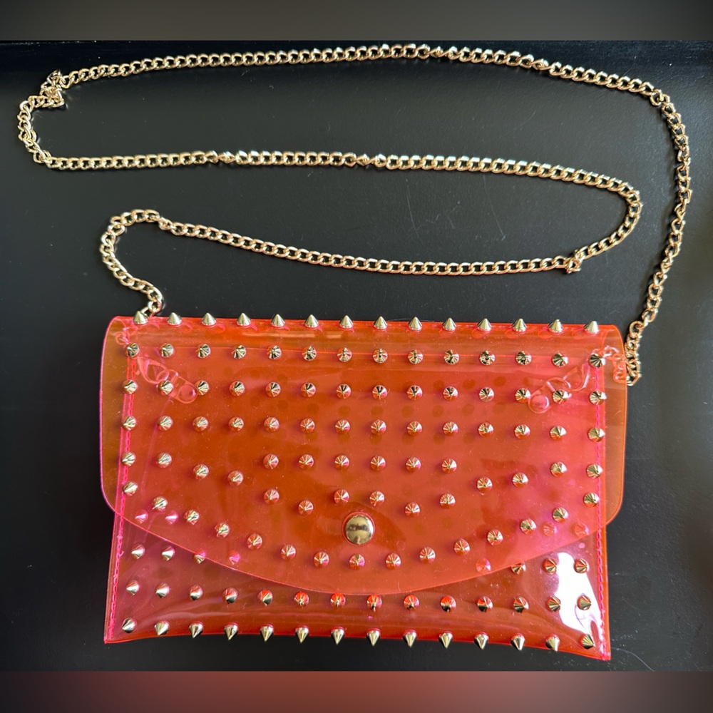 Neon pink Jelly crossbody bag with gold spikes.